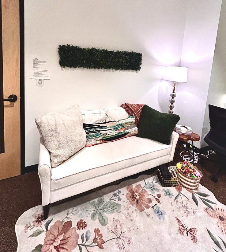 Inviting therapy office with white couch and floral rug