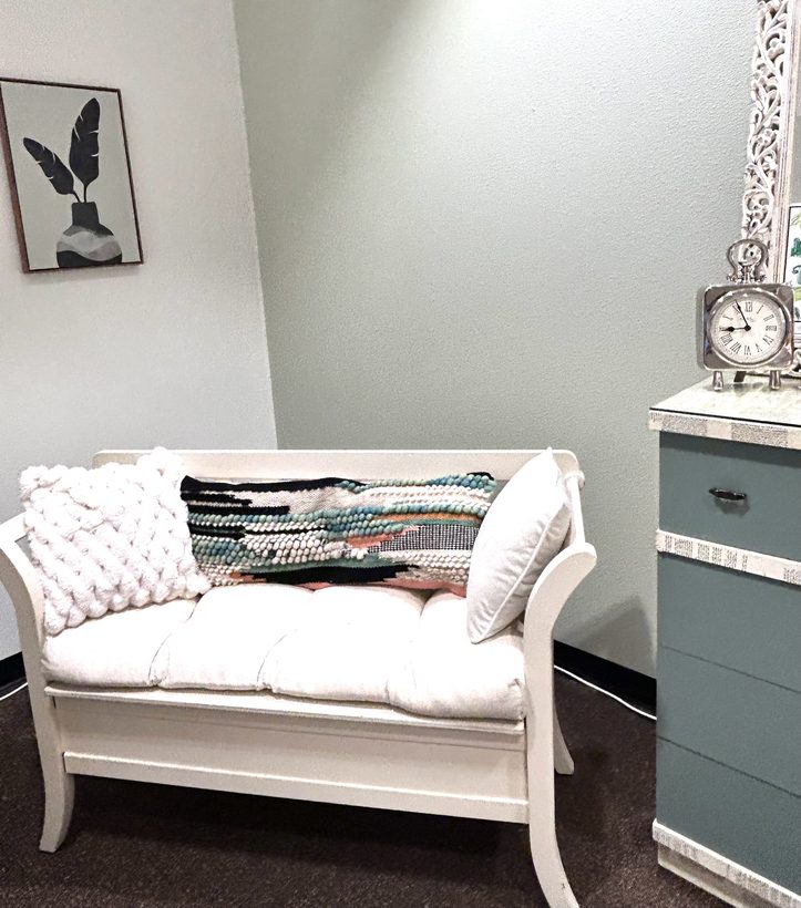 Calm therapy office with white bench and soft decor